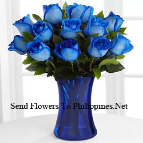 12 Blue Roses With Some Ferns In A Glass Vase