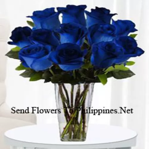 12 Blue Roses With Some Ferns In A Glass Vase