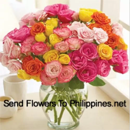 36 roses de différentes couleurs avec quelques fougères dans un vase en verre