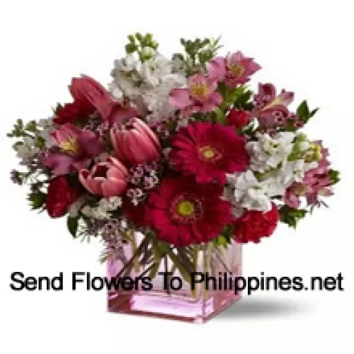 Roses rouges, tulipes rouges et fleurs assorties avec des remplisseurs saisonniers arrangés magnifiquement dans un vase en verre