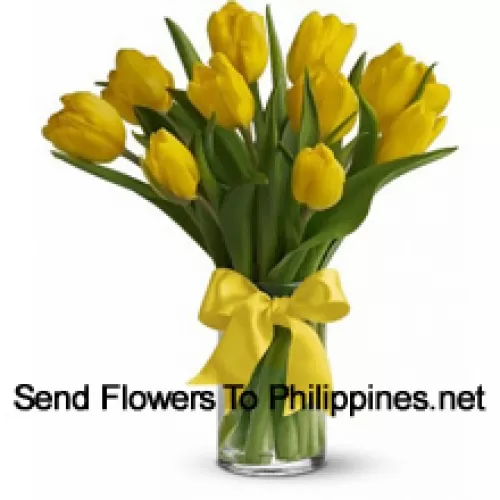 Tulipes jaunes avec des garnitures saisonnières et des feuilles dans un vase en verre - Veuillez noter que en cas de non disponibilité de certaines fleurs saisonnières, celles-ci seront remplacées par d'autres fleurs de même valeur