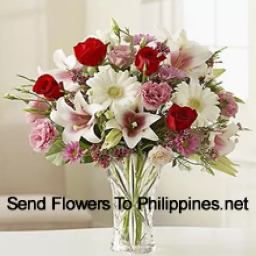 Roses rouges, œillets roses, géraniums blancs et lys blancs avec d'autres fleurs assorties dans un vase en verre