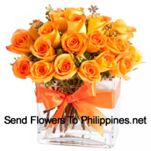 24 roses oranges avec quelques fougères dans un vase en verre