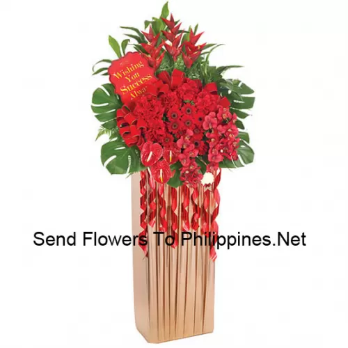 A Tall Congratulatory Stand Made Of Red Gerberas, Other Red Exotic Flowers With Ferns And Fillers