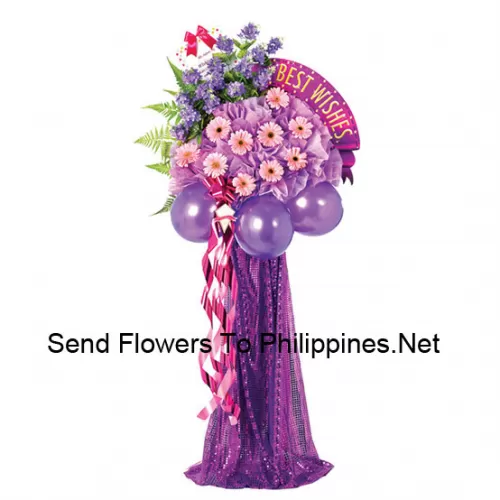 A Tall Congratulatory Stand Made Of Purple Balloons, Pink Gerberas And Other Assorted Flowers With Ferns And Fillers