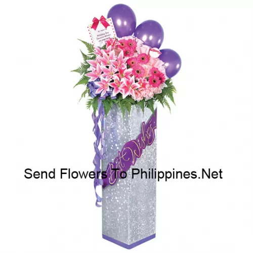 A Tall Congratulatory Stand Made Of Purple Balloons, Pink Lilies, Pink Gerberas And Other Assorted Flowers With Ferns And Fillers